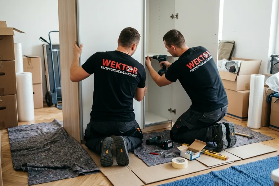 Ekipa Wektor montująca szafę po przeprowadzce